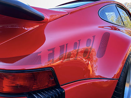 Red Porsche 911 930 Turbo rear quarter panel with stylized black turbo lettering